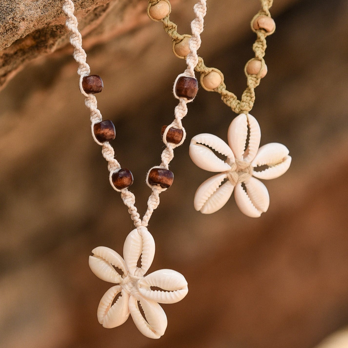 Two floral pendant necklaces with bead accents on a stone surface.