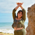 Woman in green outfit standing on a beach with ocean view
