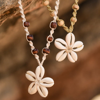 Two floral pendant necklaces with bead accents on a stone surface.